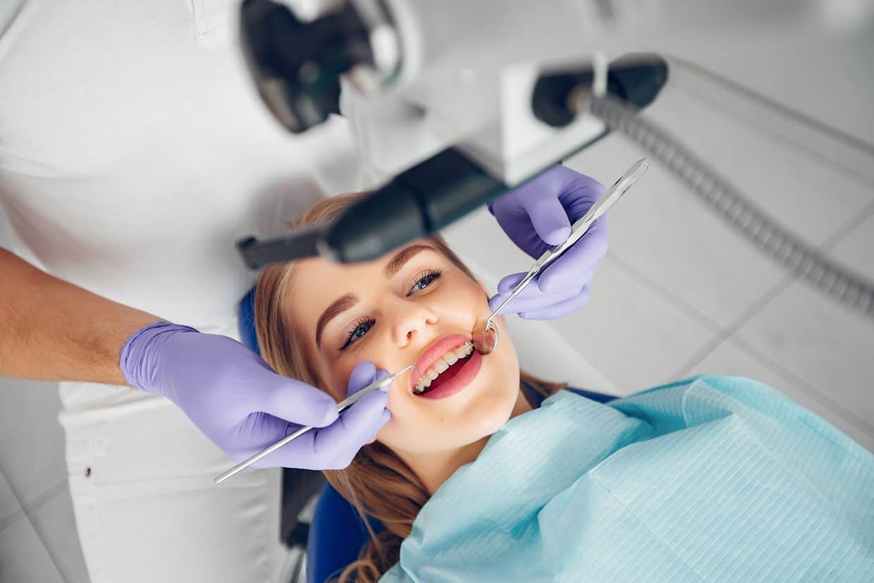 Красива жінка в кабінеті стоматолога. Жінка в уніформі. Встановити вініри, корекція щелепи, брекети, елайнери